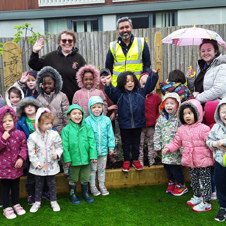 united living employees and school children standing outside in a garden